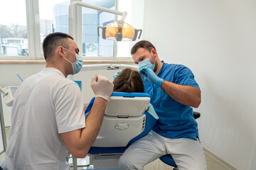 Fototapeta premium the dentist with the assistant carries out professional brushing of teeth of the patient.