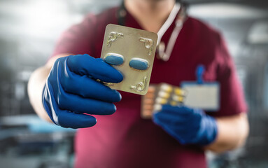 Male doctor holding  pack of different tablet pills in hospital room