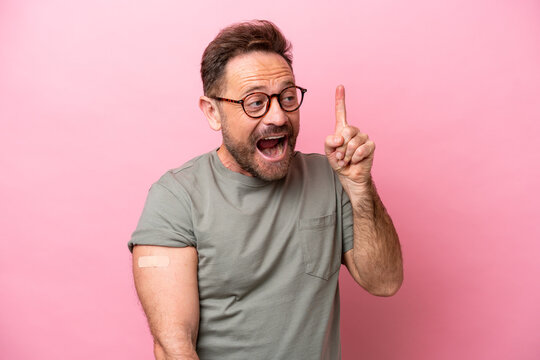 Middle age man wearing a band aids isolated on pink background intending to realizes the solution while lifting a finger up