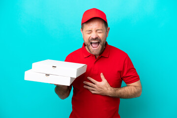 Pizza delivery man with work uniform picking up pizza boxes isolated on blue background smiling a...