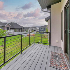 Square Puffy clouds at sunset Deck of a house with wooden planks flooring and sliding glass an