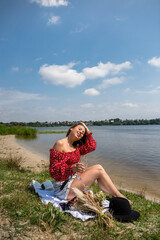 Fototapeta na wymiar Young woman alone sits near lake at summer day