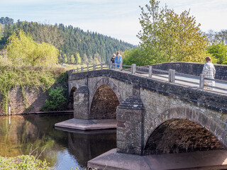 three people  walking across a three arch medieval stone bridge in the United Kingdom © Cliff