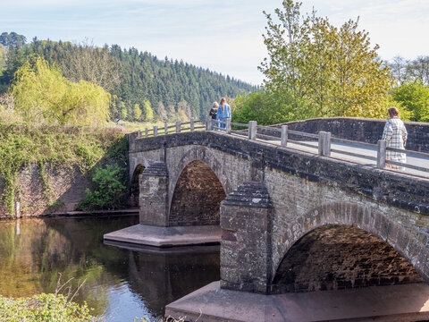 three people  walking across a three arch medieval stone bridge in the United Kingdom