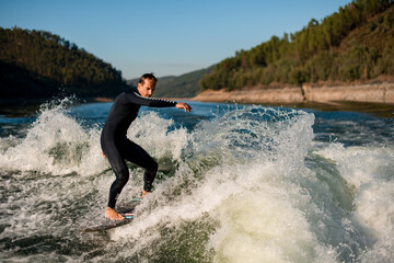 active man on wakesurf riding down the splashing wave