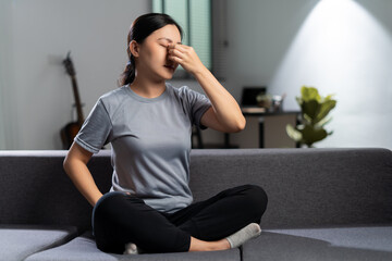 Asian woman was sick with eyes pain sitting on sofa at home.