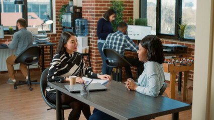 Asian employee interviewing african american candidate to explain job offer and work application. Human resources worker hiring applicant based on cv resume and business experience.