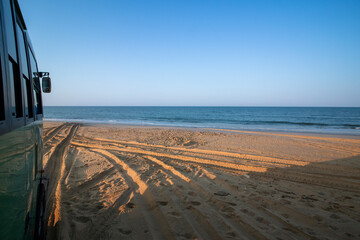 Atlantic Ocean during a sunny day, seen from an all-terrain truck driving along a beach, during a...