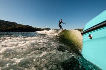 view on man on a wakesurf skillfully riding on a splashing wave