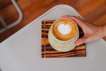 Coffee cup with latte art on the wood table.