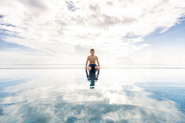 Little kid on a pools edge with a cloudly sky background