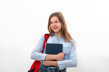 Teenager girl stands with a backpack and a tablet in her hands against white background in studio
