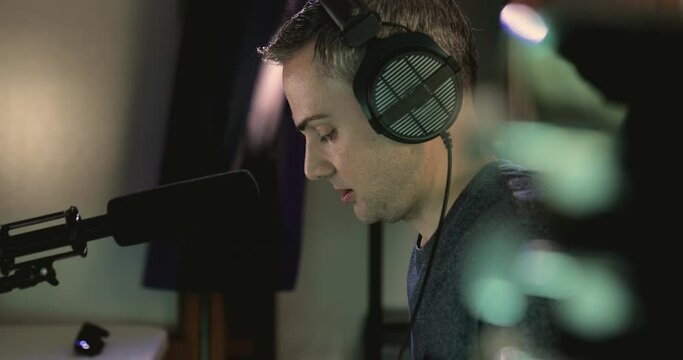 Music producer singing in order to place some vocal layers for a project during a recording session at his home studio