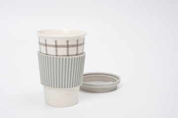 Checkered ceramic cup with rubber lid, shot against a white background.