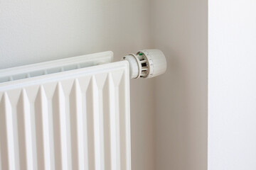 Adjusting knob on thermostat on radiator valve to save energy due to heating cost price. Temperature control.