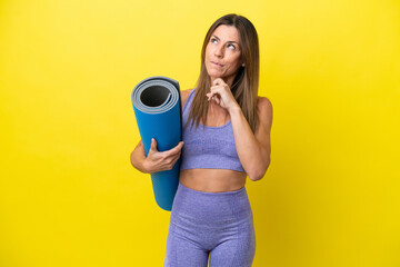 Sport woman going to yoga classes while holding a mat isolated non yellow background having doubts...