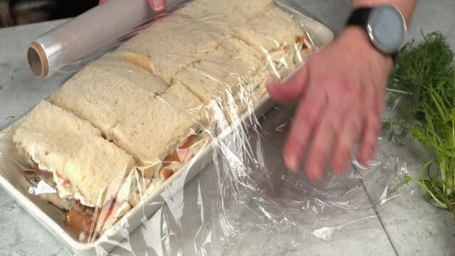 Close-up meal prep: plastic wrap added to Smorgastarta sandwich cake