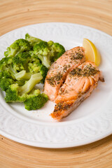 White plate with grilled salmon served with broccoli and lemon. Healthy food for family. Home dinner. Vegetarian diet diet.