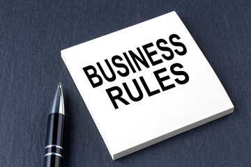 BUSINESS RULES text on the sticker with pen on the black background