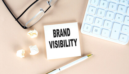 RAND VISIBILITY text on sticky with pen ,calculator and glasses on a beige background