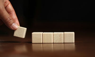 Hand picks up 5 blank wooden blocks in a row for the text area. copy space