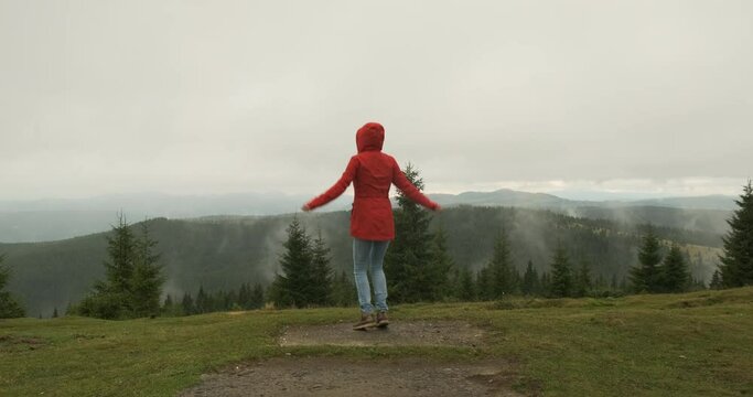 woman in a red jacket got lost in the mountains. He waves his arms, jumps and signals his whereabouts. Carpathians, Ukraine, Europe.