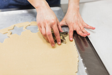 Woman cutting dough with star-shaped mold in bakery