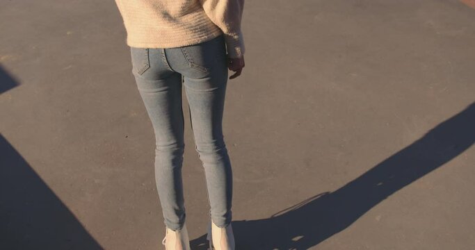 Abstract of young woman rollerskating backwards and coming to a stop. 