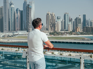 Fashionable man standing on the empty deck of a cruise liner against the backdrop of the setting sun. Closeup, outdoor. Vacation and travel concept