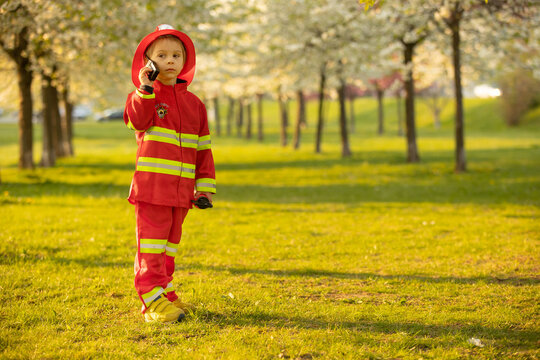Little toddler child with fireman costume in park, pretending to be real fireman, playing
