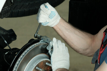 Maintenance and repair of cars in a car service center. Close-up. Replacement of brake pads. Removing the caliper.