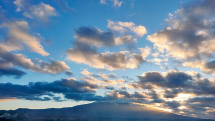 雲の隙間から見える夕日と富士山