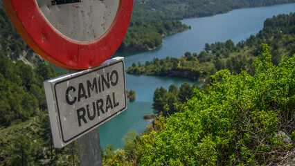 Señal de circulación y aviso de camino rural con el pantano de Guadalest de fondo