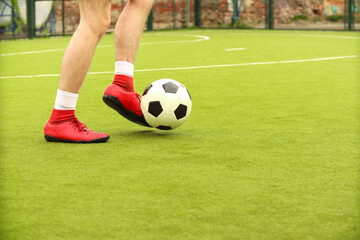 Players play mini football on the field. Legs, sneakers and a ball. Green football field.