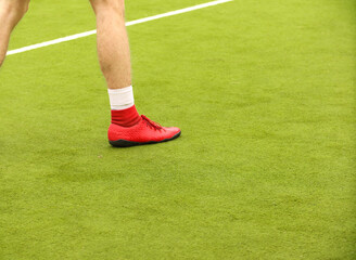 Obraz premium Players play mini football on the field. Legs, sneakers and a ball. Green football field.