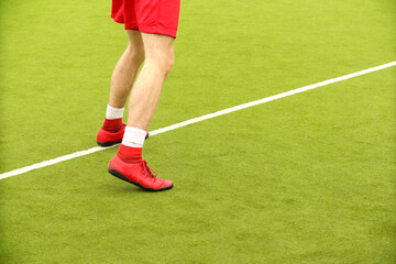 Players play mini football on the field. Legs, sneakers and a ball. Green football field.