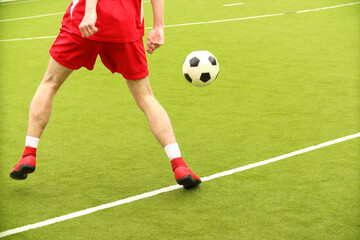 Players play mini football on the field. Legs, sneakers and a ball. Green football field.