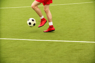 Players play mini football on the field. Legs, sneakers and a ball. Green football field.