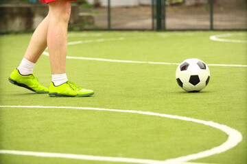 Players play mini football on the field. Legs, sneakers and a ball. Green football field.