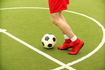 Players play mini football on the field. Legs, sneakers and a ball. Green football field.