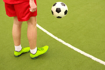 Players play mini football on the field. Legs, sneakers and a ball. Green football field.