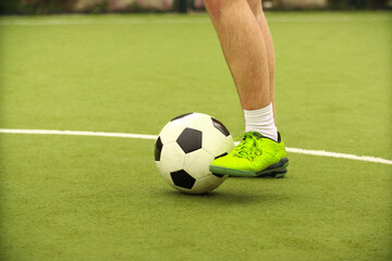 Players play mini football on the field. Legs, sneakers and a ball. Green football field.