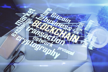 Blockchain theme hologram drawings over computer on the desktop background. Top view. Double...