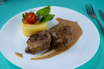 Beef cutlets meatballs with mashed potatoes on a white plate. Meat in sour cream sauce. Tomatoes and basil. Food in the restaurant. Lunch portion. Medallions.