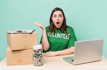 young pretty woman  looking surprised and shocked, with jaw dropped holding an object. volunteer...