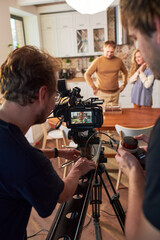Two young videographers moving video camera along slider during shooting of commercial or cooking...