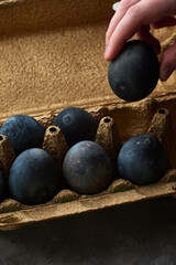 a hand takes a colored egg out of a golden box