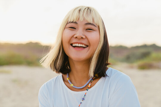 Young asian woman laughing while walking on beach