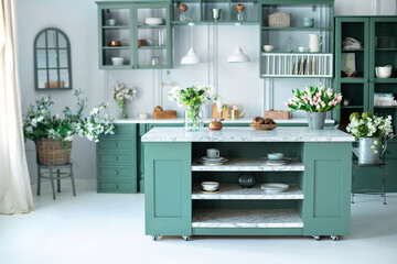 Green kitchen interior with furniture. Stylish cuisine with flowers in vase. Wooden kitchen in...