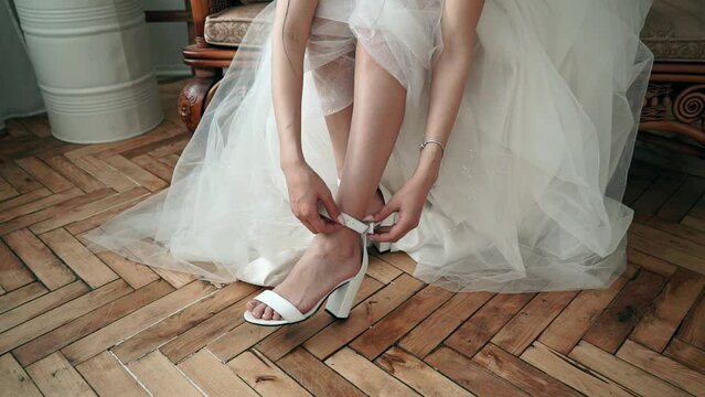 bride puts on wedding white shoes at the wedding